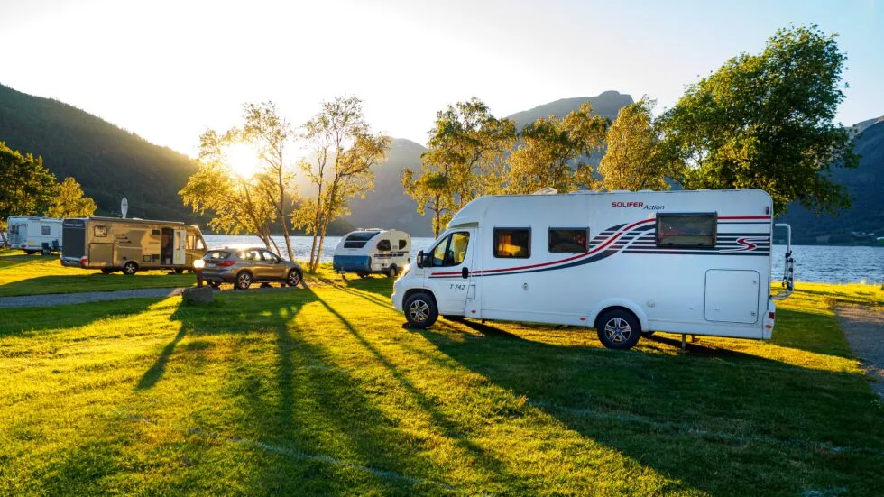 Rvs parked by a lake, at a campground.
